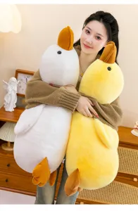 Close up of soft cute yellow and white duck plush toy hugging pillow detail in cozy room