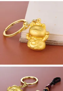 Macro view of a golden Maneki-neko lucky cat keychain with a fine matte metal finish