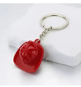 Close-up of creative red fire helmet keychain with glossy finish on white stone base