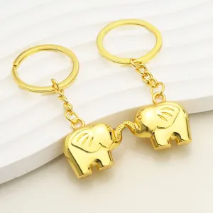 Dos llaveros de elefante dorado sobre fondo blanco, creativos recuerdos de metal para parejas