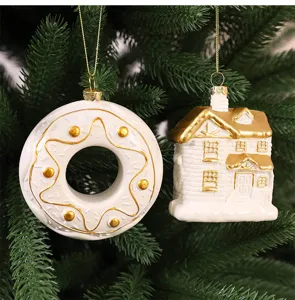 Décorations de maison et donut en céramique blanc et or sur un sapin de Noël vert