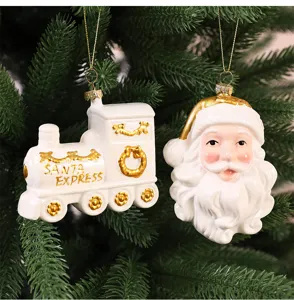 Vue détaillée des ornements de Noël festifs en céramique blanche et dorée, Père Noël et train