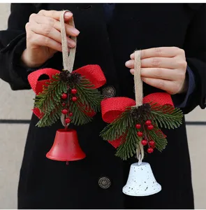 Handheld detail of Nordic Christmas bell ornaments with pine needles and red burlap bows