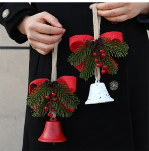 Festive detail view of Christmas bell ornaments with pine needles and red berries decor