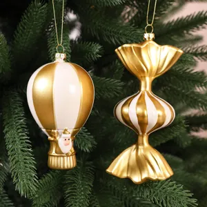 Ornements de Noël en forme de montgolfière et de bonbon dorés et blancs.