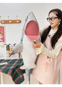 Detail view of a large simulation shark plush toy pillow, shown in a cozy home setting.