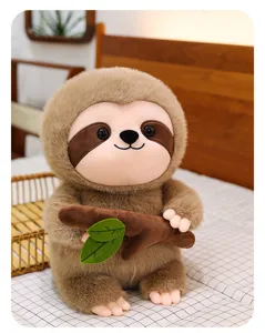 Dettaglio di peluche bradipo carino con morbida pelliccia marrone e ramo su letto accogliente.