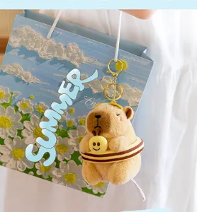 Primo piano dettagliato di un simpatico portachiavi in peluche capibara con sfondo estivo.
