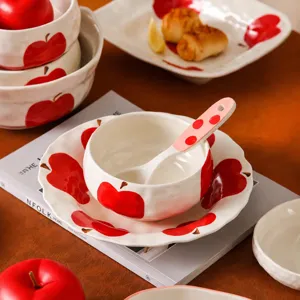 Set di stoviglie in ceramica con motivo a mela rossa, ciotole di riso, piatti e cucchiaio.