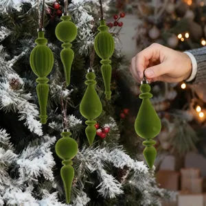 Detail view of various green flocked Christmas tree ornaments on a snowy tree branch
