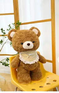 Detailed view of the cute brown plush teddy bear with a checkered bib sitting on a yellow chair.