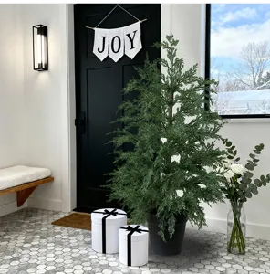 Lush artificial cypress Christmas tree in a black pot for modern home entrance decor