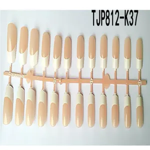 Primo piano di unghie finte french manicure con base nude e punte bianche su supporto.