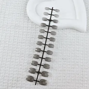 Close-up detail of short square press-on nail tips on a strip mold, unoiled and clear design.