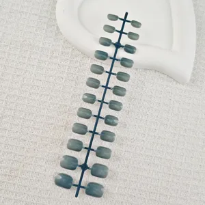 Detail view of short square false nails with cat eye grey green finish on strip holder.