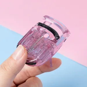 Primer plano del rizador de pestanas portatil de plastico rosa con diseno de purpurina.