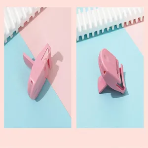 Close-up detail view of the portable mini pink plastic eyelash curler showing its folding design.