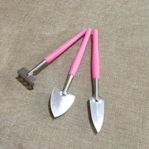 Close-up detail of mini gardening tools set, small shovel and rake with pink handles for plants.
