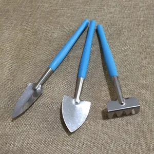 Mini gardening tool detail view featuring metal shovel and rake with blue plastic handles