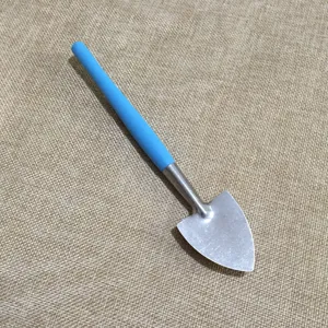 Detail shot of a mini gardening shovel with a blue plastic handle and metal blade for plants.