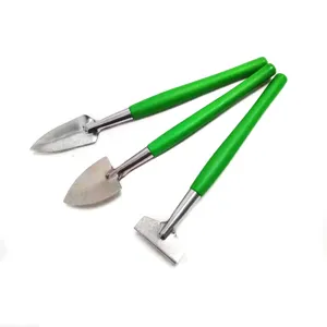 Miniature garden tools detail view showing metal shovel and green plastic handle.