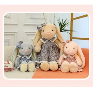Close-up of cute plush bunny toys with floral dresses and lace trim in a cozy room.