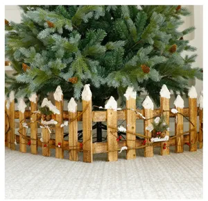 Clôture de sapin de Noël en bois rustique avec piquets enneigés et baies rouges.
