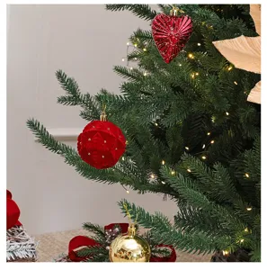 Detalle de adornos de bolas de terciopelo rojo y dorado en un árbol de Navidad iluminado