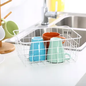 Λευκό συρμάτινο καλάθι αποθήκευσης με κεραμικές κούπες στον πάγκο της κουζίνας.