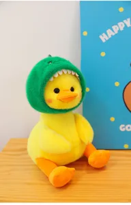 Cute yellow plush duck toy wearing green dinosaur hood, soft sitting doll detail shot.