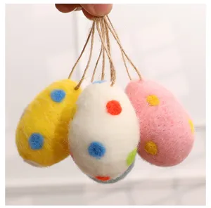 Detail of three colorful wool felt Easter eggs with spotted patterns and hanging strings