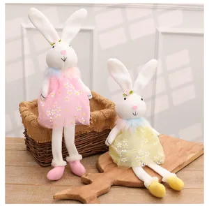 Pair of plush Easter bunnies in pink and yellow floral dresses on a wooden table