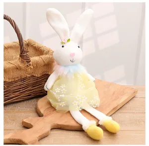 Close-up of cute Easter plush rabbit doll decor in yellow daisy dress on wood board