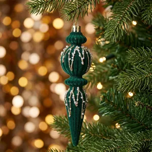 Close-up of a green velvet beaded Christmas drop ornament hanging on a festive tree