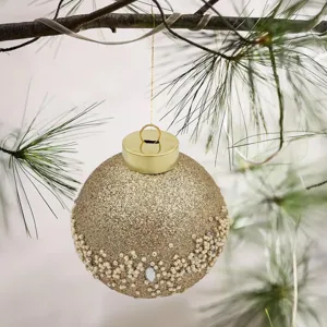 Primer plano elegante de una bola de Navidad dorada con purpurina y detalles de perlas y gemas