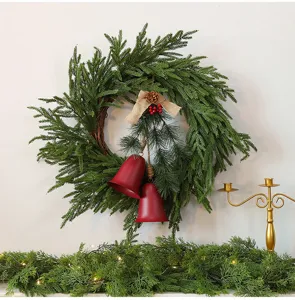 Gedetailleerd zicht op een groene kerstkrans met rode bellen en dennenappels.