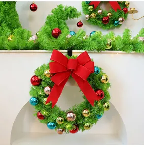 Vue détaillée d'une couronne de Noël verte avec des boules colorées et un grand nœud rouge