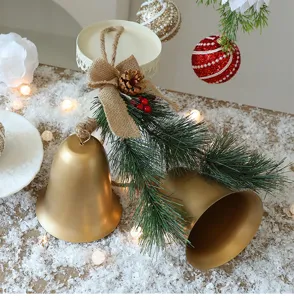 Gouden kerstbellen met een strik van jute en dennennaalden op sneeuw
