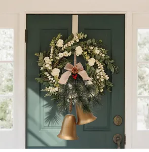 Detail van gouden kerstklokken met dennennaalden en linnen strik op een groene deur