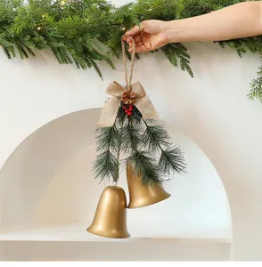 Gedetailleerde weergave van gouden kerstklokken met dennennaalden en een jute strik
