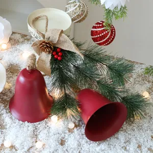 Detailopname van rode kerstklokken met dennennaalden en jute strik op kunstmatige sneeuw
