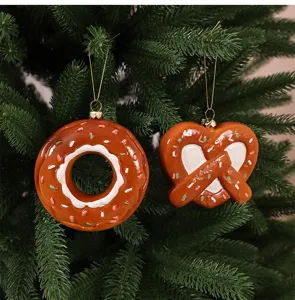 Close-up of doughnut and pretzel Christmas ornaments hanging on a green pine tree