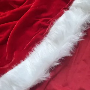 Primo piano di tessuto in velluto rosso con bordo in pelliccia sintetica bianca per mantello natalizio.