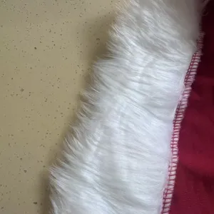 Primo piano dettagliato del tessuto rosso del costume di Natale con pelliccia sintetica bianca.