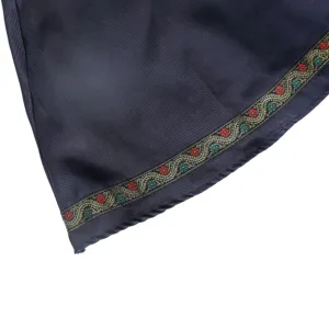Close-up detail view of traditional dirndl dress skirt hem with embroidered floral trim.