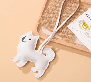 Détail d'un charm de chien Samoyède en cuir PU blanc avec sangle pour sac à main.