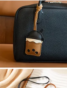 Close-up of a cute bubble tea cup leather charm accessory hanging on a black pebbled handbag
