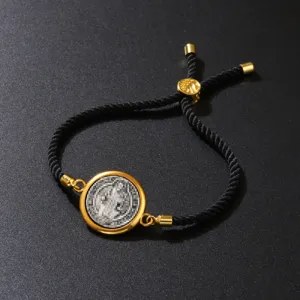 Detail of adjustable black braided cotton rope bracelet with vintage gold pendant