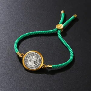 Close-up view of a green twisted cotton rope bracelet with a gold circular pendant.