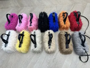 Borse tote in ecopelliccia shaggy in vari colori con manici neri esposte su pavimento legno.